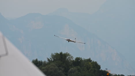 Aerobatic-Glider-landing-on-ground,-seen-behind-plane-wings,-focus-on-background