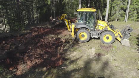 Tractor-Jcb-Trabajando-En-El-Bosque,-Sacando-Raíces-De-árboles-Y-Amontonándolas