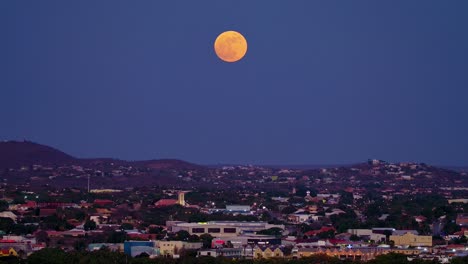 Pan-up-across-curacao-container-industrial-port-zone-terminal-to-red-orange-supermoon-above-city-of-willemstad