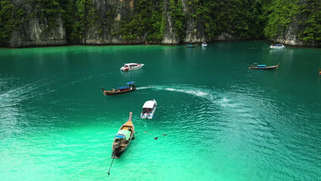 Tourists-sailing-across-Phi-Phi-Island-on-longtail-boats-and-speedboats,-Diving-trips-at-Pi-Leh-Bay-,-Thailand,-Aerial-View