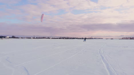 A-male-athlete-in-sports-outfit-is-doing-snow-kiting-on-beautiful-winter-landscape.