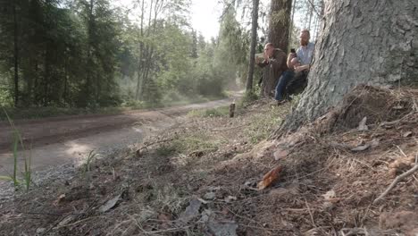 Los-Espectadores-Del-Rally-Wrc-Filman-En-Sus-Teléfonos-Lo-Rápido-Que-Vuela-El-Auto-De-Rally-A-Alta-Velocidad-En-Un-Camino-De-Grava-Rodeado-De-Bosque,-Se-Ve-Una-Nube-De-Polvo-A-La-Luz-Del-Sol