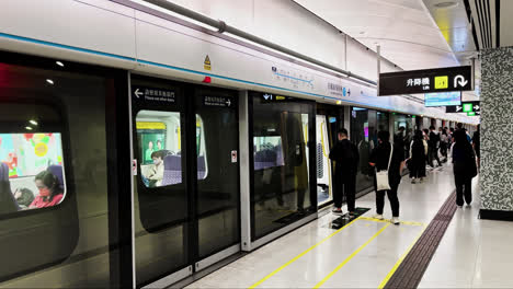 Zeitlupe-Der-MTR-Station-In-Hongkong,-Während-Sich-Die-Zugtüren-öffnen-Und-Passagiere-Einsteigen