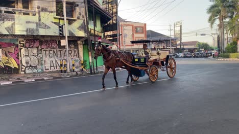 Se-Puede-Ver-El-Transporte-Andong-Pasando-Y-Montones-De-Basura-Al-Costado-De-La-Carretera-De-Mataram,-Y-Se-Puede-Ver-Un-Cartel-Adjunto-Con-Las-Palabras-&quot;basura-Turística-De-Jogja&quot;.