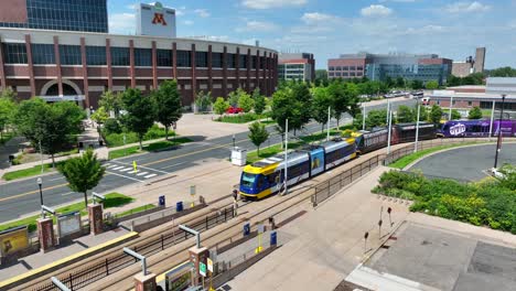 Tren-De-Transporte-Público-En-El-Campus-De-La-Universidad-De-Minnesota-Con-El-Estadio-Huntington-Bank-En-Segundo-Plano.