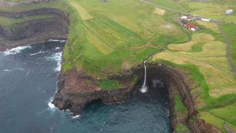 Aerial-top-down-shot-of-falling-Mulafossur-waterfall-into-Atlantic-Ocean-and-green-landscape-on-top