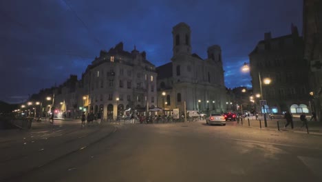 Nachtleben-In-Den-Straßen-Von-Besançon-In-Frankreich,-Mit-Autos,-Straßenbahnschienen,-Passanten,-Nachthimmel-Und-Straßenlaternen