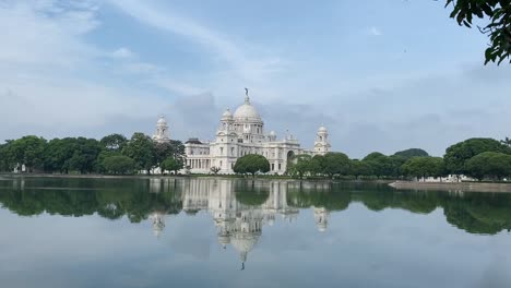 Aufnahme-Eines-Weißen-Marmordenkmals-Namens-Victoria-Memorial-Compound-Mit-Einem-See-Im-Vordergrund-In-Kalkutta,-Westbengalen,-Indien-An-Einem-Bewölkten-Tag