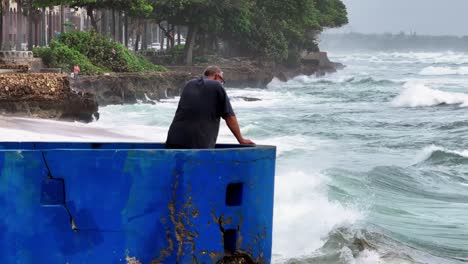 Adult-Man-watching-giant-waves-during-hurricane-season-in-Dominican-Republic---wide-shot