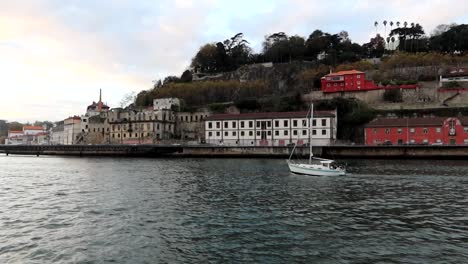 Verfolgung-Eines-Einsamen-Bootes,-Das-Bei-Sonnenuntergang-Auf-Dem-Fluss-Douro-In-Porto-Segelt