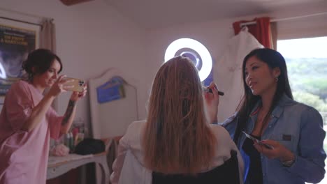 Mujer-Joven-Filmando-A-La-Novia-Con-La-Cámara-Del-Teléfono-Inteligente-Durante-La-Aplicación-De-Maquillaje.
