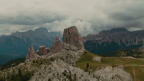 Parallax-drone-shot-massive-rock-formations-with-distant-tall-mountains-in-the-background,-cloudy-day,-cinematic-color-grade