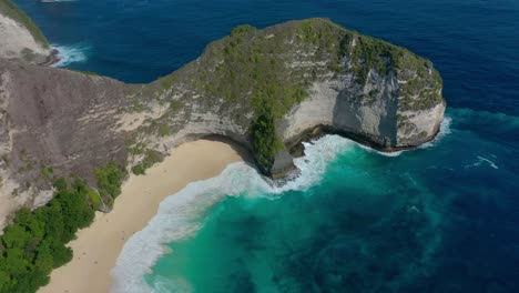 Bali's-exotic-charm-is-distilled-in-every-moment-of-the-aerial-footage,-Discover-Diamond-Beach-With-its-ivory-sands,-crystalline-waters,-iconic-rock-formations,-and-true-tropical-paradise