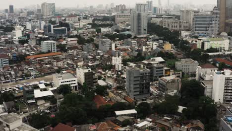 Aerial-birds-eye-shot-of-Jakarta-City-with-traffic-on-intersection-in-downtown-during-cloudy-day,-Capital-of-Indonesia