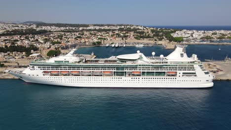 Huge-white-cruise-ship-in-Kolona-harbor-travel-island-Rhodes,-aerial-backward