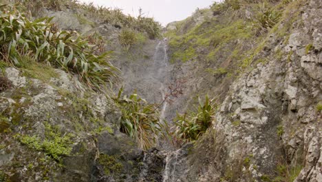 Low-angle-view-of-a-small-waterfall-flowing-down-a-cliff-in-New-Zealand