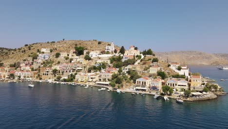 Mediterranean-city-on-island-Symi-in-Greece,-aerial-backward-establisher