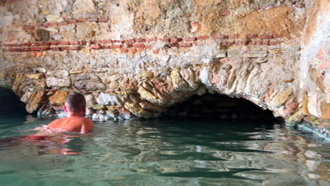 Baños-Romanos-De-Casares-Manilva,-Gente-Nadando-En-Manantiales-Naturales-Curando-Agua-De-Azufre-En-España,-Buenos-Beneficios-Para-La-Salud,-Toma-De-4k