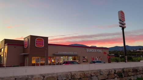 Hermosa-Puesta-De-Sol-Rosa-Anaranjada-En-El-Restaurante-Burger-King-En-Estepona,-España,-Increíble-Puesta-De-Sol-En-Auto-King-Drive,-4k-Panorámica-Hacia-La-Izquierda