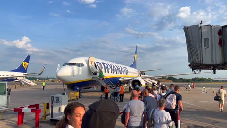 Gente-Esperando-Lentamente-En-La-Fila-Y-Abordando-Un-Gran-Avión-Boeing-De-Ryanair-En-El-Aeropuerto-Internacional-De-Bristol-En-Un-Día-Soleado,-Tiempo-De-Vacaciones,-Toma-De-4k