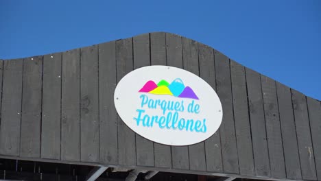 Colourful-Parques-De-Farellones-circular-disc-signage-hanging-from-wooden-plank-barn-style-roof-apex