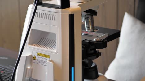 Slow-motion-tilting-shot-revealing-a-microscope-sitting-on-a-desk-within-a-clinic