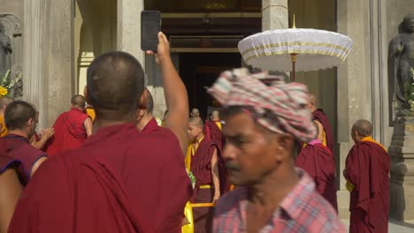 Buddhist-monks-procession-on-the-occasion-of-Holy-Dalai-Lama's-88th-birthday-at-Mahabodhi-Temple,-Buddhist-monk-recording-videos-of-Golden-Buddha-inside-Mahabodhi-Temple