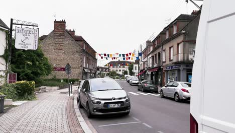 Hängende-T-Shirts-An-Einem-Bewölkten-Tag-Draußen-über-Der-Straße-In-Chateauneuf-sur-Loire-In-Frankreich-Mit-Einer-Reihe-Von-Steinhäusern-Und-Auf-Der-Straße-Geparkten-Autos