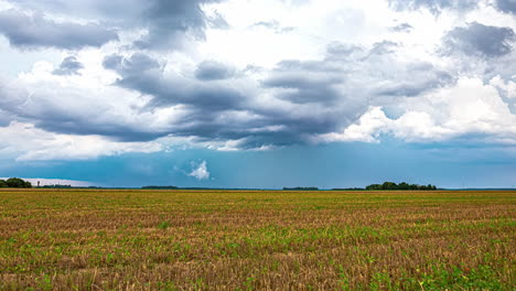 Blue-rain-clouds-flowing-over-rural-agriculture-landscape,-time-lapse-view
