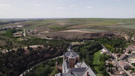 Drone-of-Alcázar-de-Segovia,-standing-in-striking-contrast-to-the-landscape