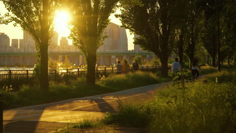 Seoul-Han-River-Park-Bei-Sonnenuntergang---Menschen-Gehen-Und-Radeln-Abends-Mit-Dem-Fahrrad-Und-Genießen-Den-Sommertag-Im-Untergehenden-Sonnenlicht