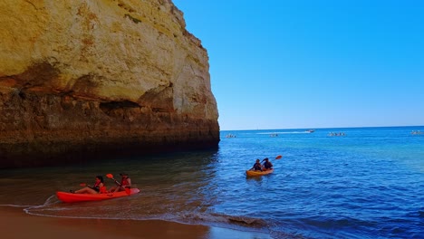 People-row-their-canoes-ashore-at-Benagil-Beach,-Central-Algarve,-Portugal