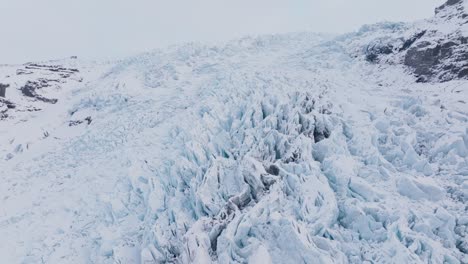 Vista-Aérea-Del-Paisaje-Sobre-Formaciones-De-Hielo-En-El-Glaciar-Falljokull-Cubierto-De-Nieve,-Islandia,-Al-Atardecer