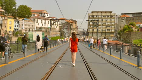 Begleitende-Schöne-Frau-In-Rot,-Die-Auf-Der-Brücke-Dom-Luis-I-In-Porto,-Portugal,-Spaziert