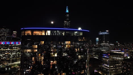 Aerial-view-of-urban-city-life-inside-a-reflecting-condo,-revealing-the-Sears-tower,-night-in-Chicago,-USA