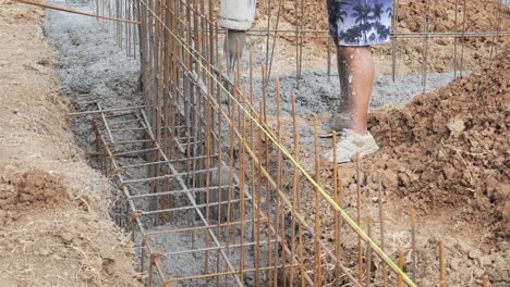 Man-pours-wet-concrete-into-house-foundation-rebar-reinforcement-trench