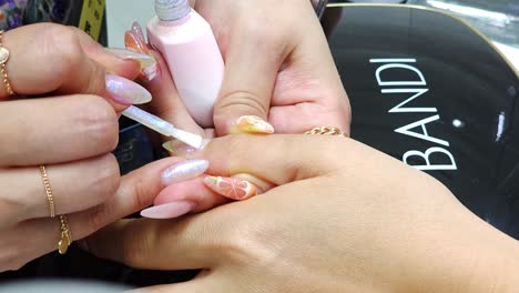 Nail-Art-Technician-Performing-Manicure-Painting-at-Beauty-Salon---Hands-Closeup
