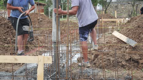 Builder-team-pours-wet-concrete-into-reinforced-house-foundation-footings
