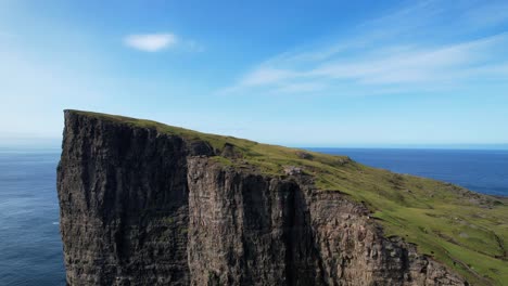 Drone-ascending-shot-of-green-meadow-on-top-of-Traelanipa-Cliff-with-ocean-view-during-sunny-day,-Faroe-Islands