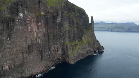 Aerial-backwards-shot-showing-steep-broken-cliffs-on-Vagar-Island-during-mystic-cloudy-day,-Faroe-Islands