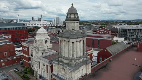 Vuelo-Aéreo-De-Drones-Alrededor-De-La-Torre-Del-Reloj-En-La-Azotea-Del-Edificio-De-Posgrado-De-Resonancia-Magnética-De-La-Universidad-De-Manchester-Con-Un-Horizonte-Del-Centro-De-La-Ciudad-De-Manchester