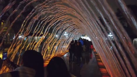 People-Walking-Inside-The-Tunnel-Fountain-Of-Magic-Water-Circuit-At-Night-In-Lima,-Peru