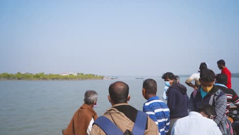 People-standing-on-a-traditional-ferry-boat-crossing-river-at-Sunderban-islands-in-24-Parganas-West-Benagal-India