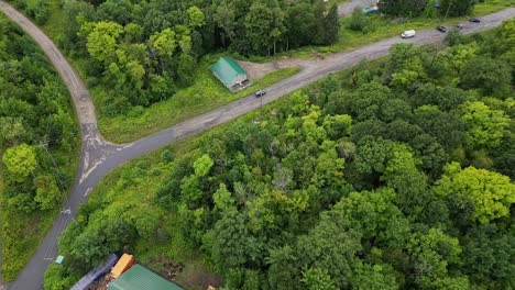 Vehicle-Driving-On-Country-Road-Surrounded-With-Lush-Green-Trees---aerial-drone-shot