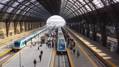People-by-trains-inside-Retiro-Station-in-Buenos-Aires,-aerial-push-in