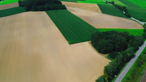 aerial-shot-of-plowed-farmland-and-green-fields,-4k