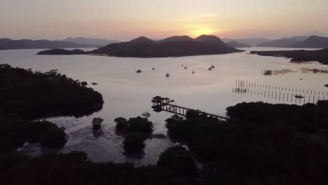 Cinematic-aerial-footage-tilting-up-filming-the-sunset-with-boats,-the-ocean-and-mountains-in-view,-Palawan,-Philippines,-Asia,-Drone