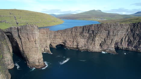 Aerial-pull-back-shot-reveals-the-lake-above-the-ocean-in-Faroe-Islands