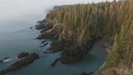 Eine-Malerische-Luftaufnahme-Der-Kühnen-Küste-Von-Maine-Zeigt-Nebelumhüllte-Bäume