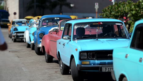 Reihe-Alter-Retro-Autos-Am-Straßenrand-In-Havanna,-Kuba,-Mit-Einer-Person,-Die-Auf-Sie-Zugeht
